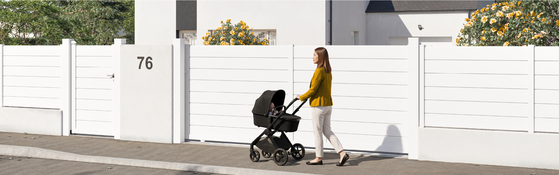 une femme avec une poussette marche devant une clôture en aluminium blanche